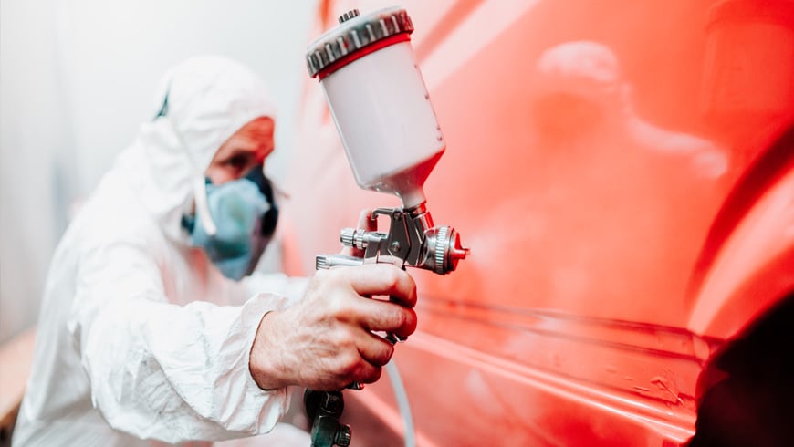 auto body tech painting side of red car