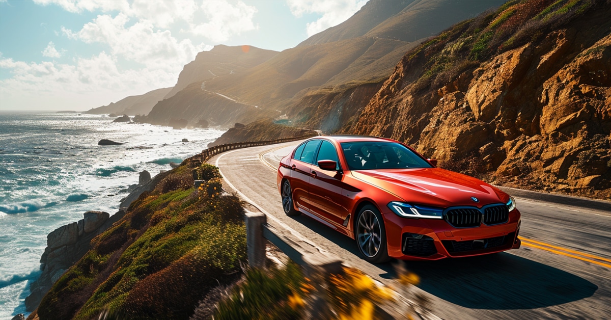 Red BMW 530i driving fast on a scenic ocean highway