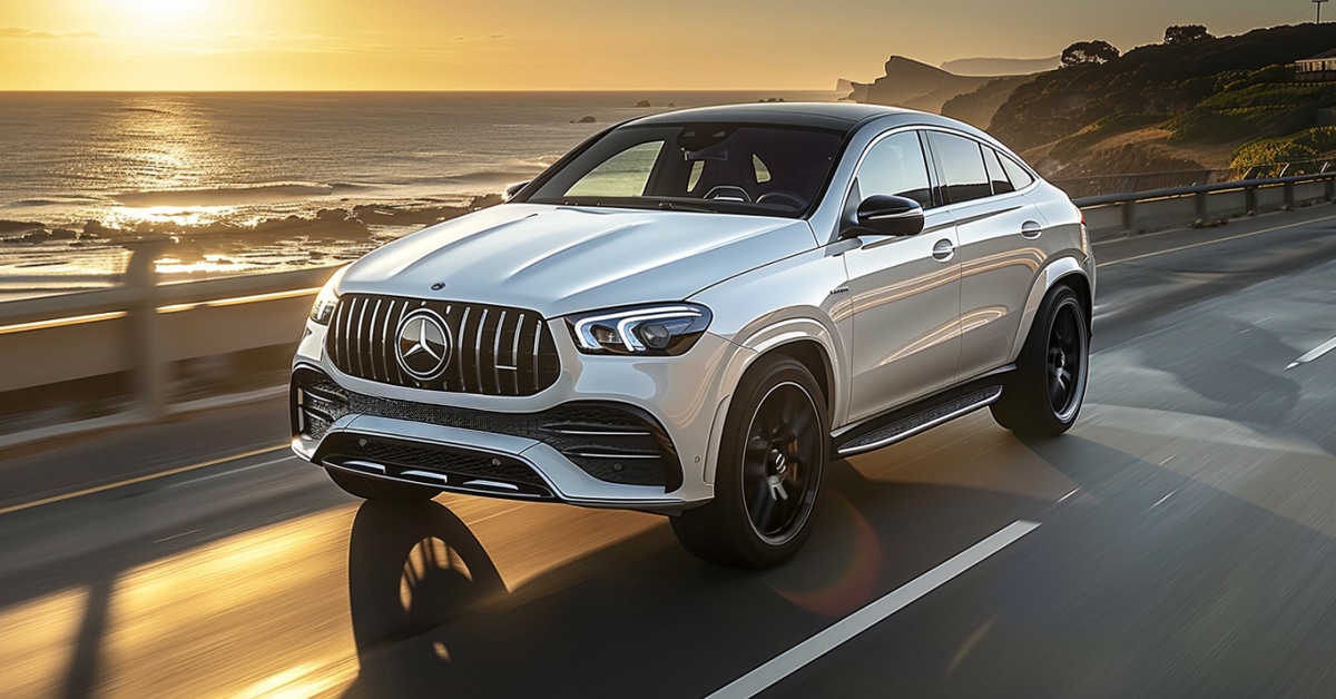 White 2023 Mercedes-Benz AMG GLE 53 driving on coastal highway at sunset