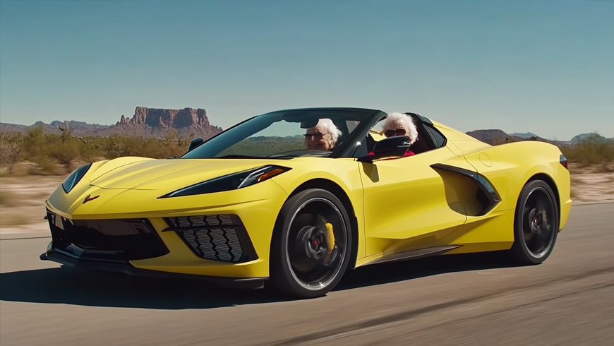 white hair seniors driving fast in yellow 2024 Chevy Corvette