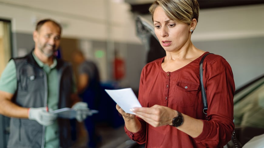 woman with shocked look after seeing car repair bill